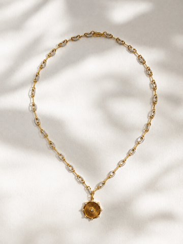 Gold necklace with a pendant on a light background