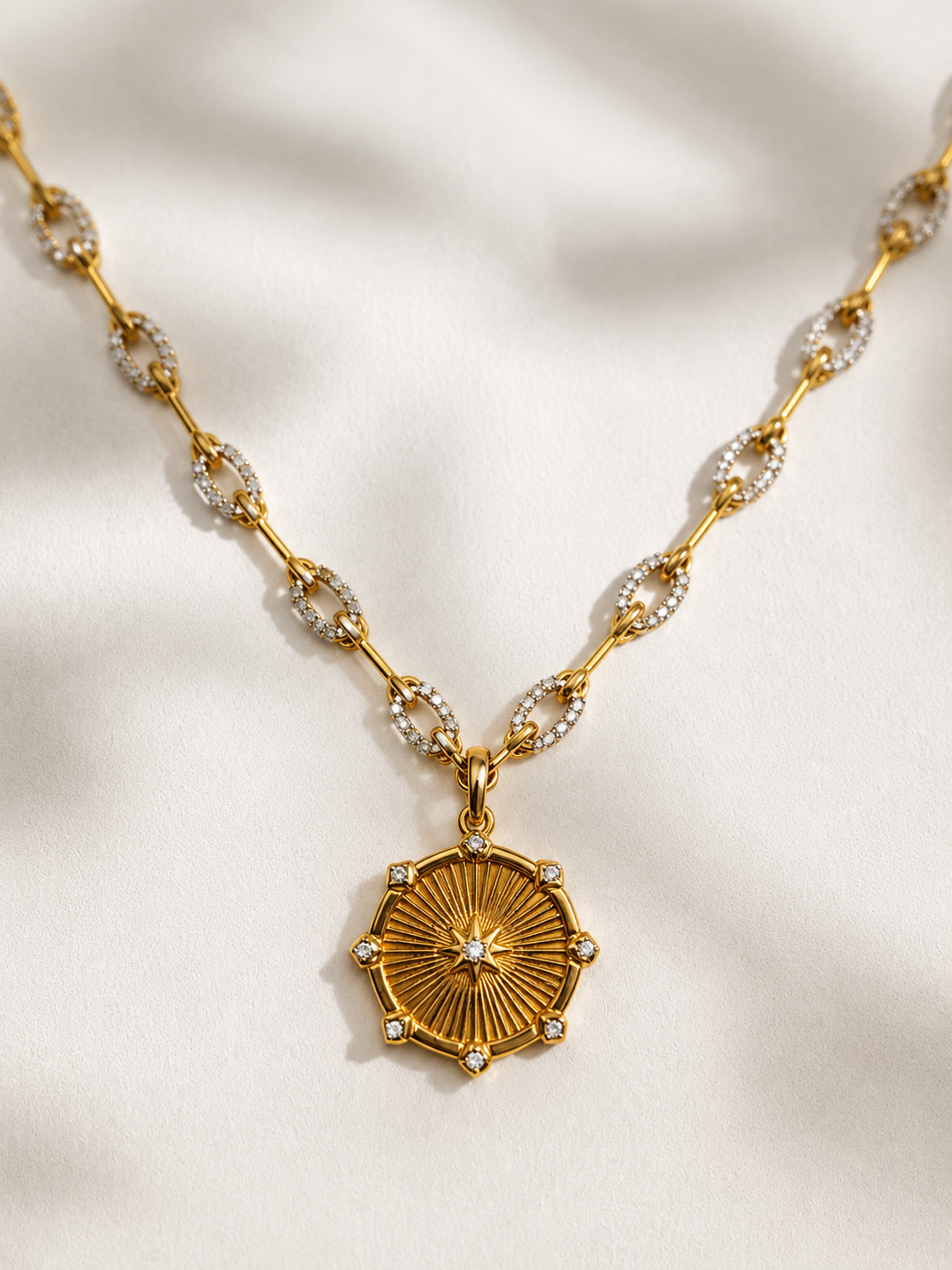 Gold necklace with a decorative pendant on a light fabric background