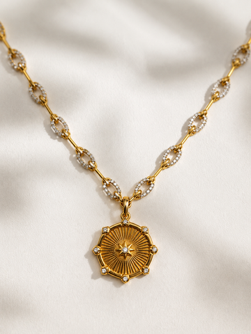 Gold necklace with a decorative pendant on a light fabric background