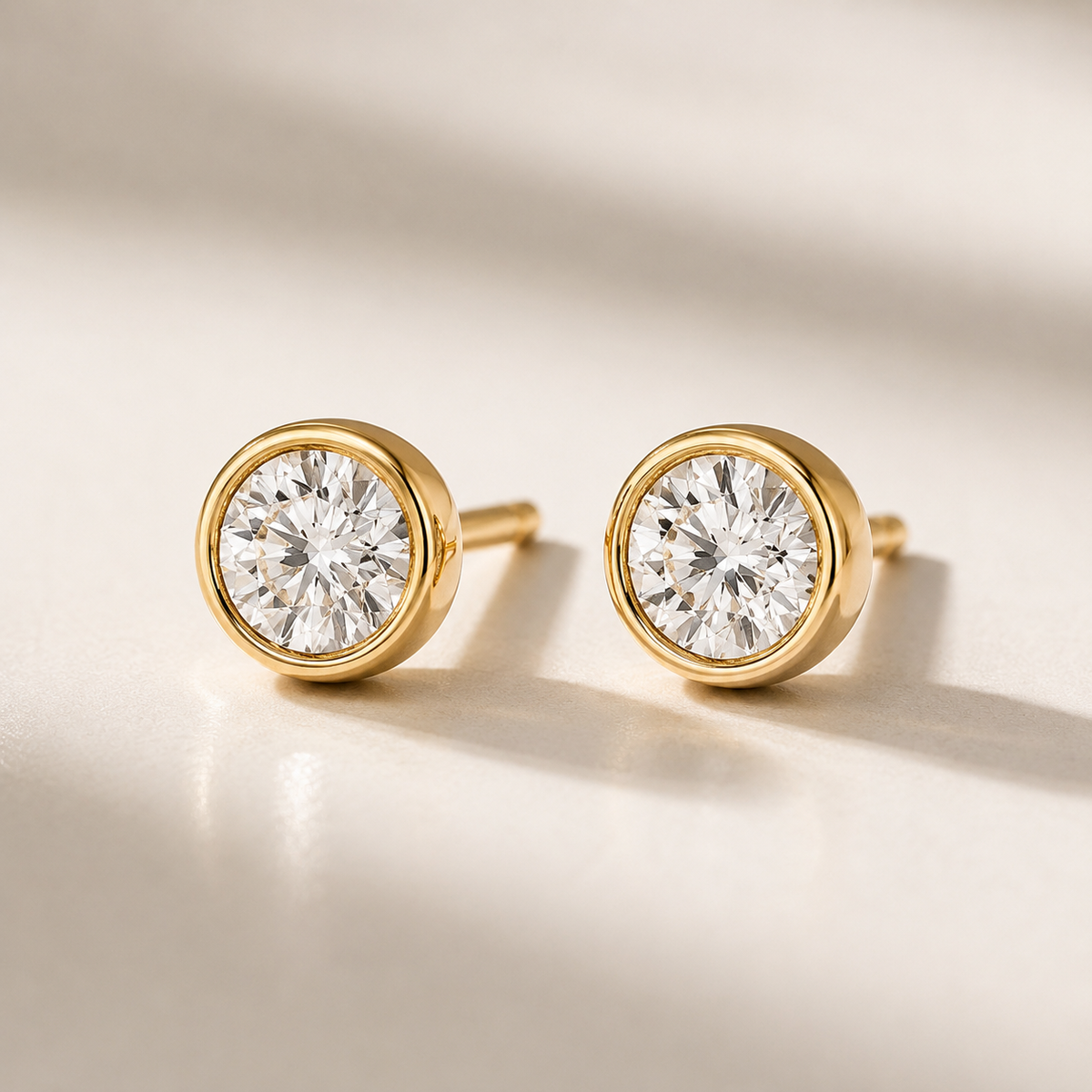 Gold diamond stud earrings on a beige background