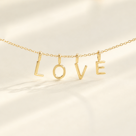 Gold necklace with 'LOVE' letters on a beige background